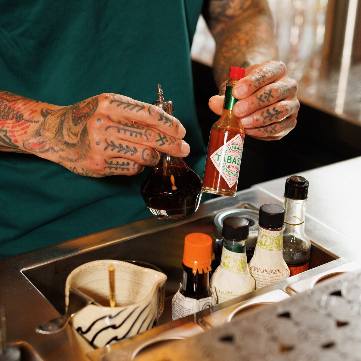 Bartender reaching for a bottle of bitters in the station's garnish rail